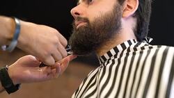 Barber trimming beard of customer in hair salon Stock Footage
