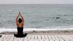Young woman doing yoga at the seaside in morning Stock Footage