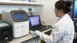 Lab assistant working with touchscreen and drawer machine for testing samples News Clip