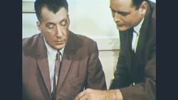 1960s: Two men review a catalog and one man points to a picture of a machine Stock Footage
