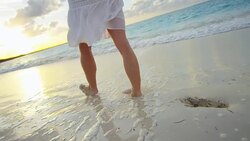 Female Caucasian legs barefoot on beach at sunset Stock Footage