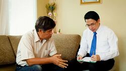 Depressed Asian senior man sitting on the couch visiting psychiatrist doctor for examination Stock Footage