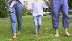 Barefoot kid and parents walking on grass Stock Footage