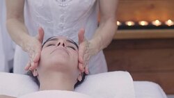 Close up of the face of a beautiful woman who gets her face massaged by an expert masseuse in a wellness center. Concept of: spa, relaxation, rest, massage Stock Footage