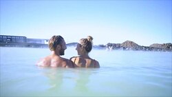 Geothermal spa. Young couple relaxing in hot spring pool in Iceland. people enjoying bathing in a blue water lagoon Icelandic tourist attraction, Video SLOW MOTION Stock Footage