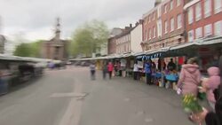 High Street with people, shops and market stalls News Clip