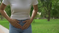 Female feeling lower abdominal pain, walking in park, symptom of cystitis Stock Footage
