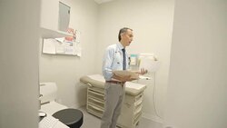 Male doctor discussing medical chart in clinic exam room Stock Footage