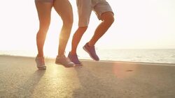 SLOW MOTION: Young girlfriend and boyfriend jogging on a sunny day near the sea. Stock Footage