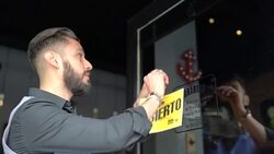 Barber hanging open sign in Spanish on glass door Stock Footage
