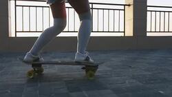 Young stylish attractive woman skateboarding at sunrise on seafront, slow motion, close up shot Stock Footage