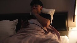 Sleepy young man using mobile phone on bed in the night, addiction concept Stock Footage