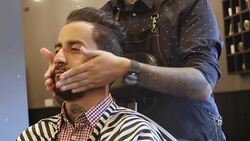 Barber applying aftershave to customer in salon Stock Footage