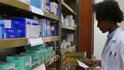 Chemist with prescription picking up box from rack Stock Footage