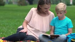 Happy mother and smart son reading together and discussing plot, home education Stock Footage