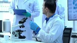 Scientist is looking through microscope with colleagues working in modern laboratory or medical center together. Concept of science, testing development and lab industry. Stock Footage