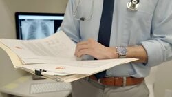 Male doctor reviewing medical chart and test results in clinic Stock Footage