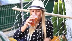 Blonde Woman Drinking Beer in Hammock Stock Footage
