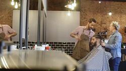Barbers preparing customer for haircut in salon Stock Footage