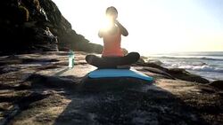 Relaxed young woman practicing yoga next to the beach Stock Footage