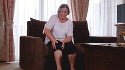 Elderly woman suffering from pain in knee at home Stock Footage
