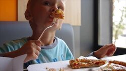 Cute child eating pizza with appetite in fast food restaurant. Real time full hd video footage Stock Footage