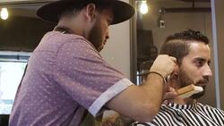 Barber cutting customer's hair with electric razor Stock Footage