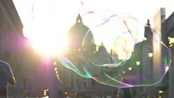 SLOW MOTION: Male street performer making large soap bubbles near the cathedral. Stock Footage