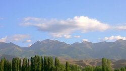 Mountain peaks and green trees on blue sky landscape, timelapse Stock Footage