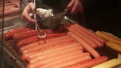 Sausages on plate grill in 4K. Picking up multiple hot dogs on plate grill Stock Footage
