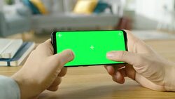 First Person Close-up of the Man Holding Green Screen Smartphone in Landscape Mode and Playing Game with His Thumbs. Stock Footage