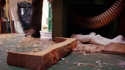 A large chunk of sawed wood noisily drops to the floor of a workshop. Stock Footage