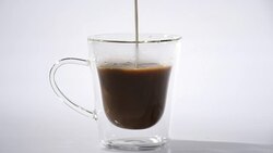 Pouring milk into cup of hot coffee Stock Footage