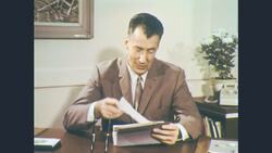 1960s: Man at desk is handed roll of documents Stock Footage