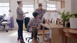 Creative designers working, designing bottle label in open plan office Stock Footage