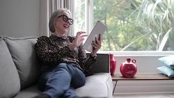 Mature adult female laughing with a digital tablet Stock Footage