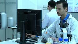 Scientist male sitting and is looking monitor screen with through microscope working in modern laboratory or medical center. Concept of science, testing development and lab industry. Stock Footage