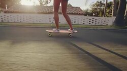Close up slow motion shot of girls feet riding skateboard at sunset with lens flare Stock Footage