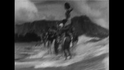 Hawaii, 1952: Beachgoers enjoy surfing as the Aloha Tower stands in Hawaii's capital, Honolulu Stock Footage