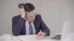 Slow motion - Businessman upset at desk in office. Asian businessman being depressed by working in office. Yong business man to think and not Work with stress Pretending to put his hand to the head. Stock Footage