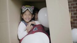A little girl playing cardboard box Stock Footage