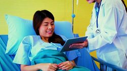 Young Asian female doctor and woman patient lying in bed while discussing and consultation medical examination at hospital room , Healthcare and medical concept, Doctor and patient Stock Footage