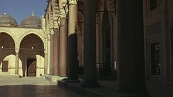 WIDE ANGLE OF INTERIOR STONE COURTYARD. PILLARS OR COLUMNS. STRIPED POINTED ARCHES. ISLAMIC ARCHITECTURE. SULEYMANIYE MOSQUE. DOMES VISIBLE IN BG. Stock Footage