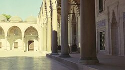 WIDE ANGLE OF INTERIOR STONE COURTYARD. PILLARS OR COLUMNS. STRIPED POINTED ARCHES. ISLAMIC ARCHITECTURE. SULEYMANIYE MOSQUE. DOMES VISIBLE IN BG. Stock Footage