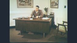 1960s: Man in suit opens glass door of business and enters Stock Footage