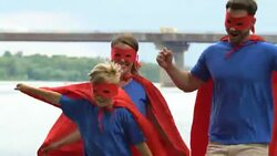 Happy family dressed like superheroes, supportive parents standing behind son Stock Footage