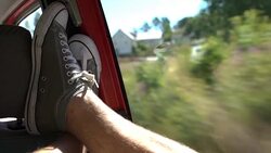 A young man enjoys traveling by car throws her legs on the window. Stock Footage