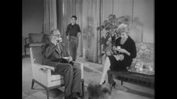 1960s: Well-dressed man and woman perch on living room furniture sipping coffee Stock Footage