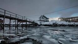 Ice cracked floating on coastline with wooden house in blizzard at Lofoten islands, Norway Stock Footage