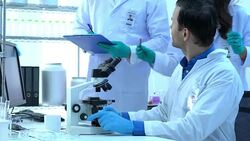 Scientist is looking through microscope with colleagues working in modern laboratory or medical center together. Concept of science, testing development and lab industry. Stock Footage